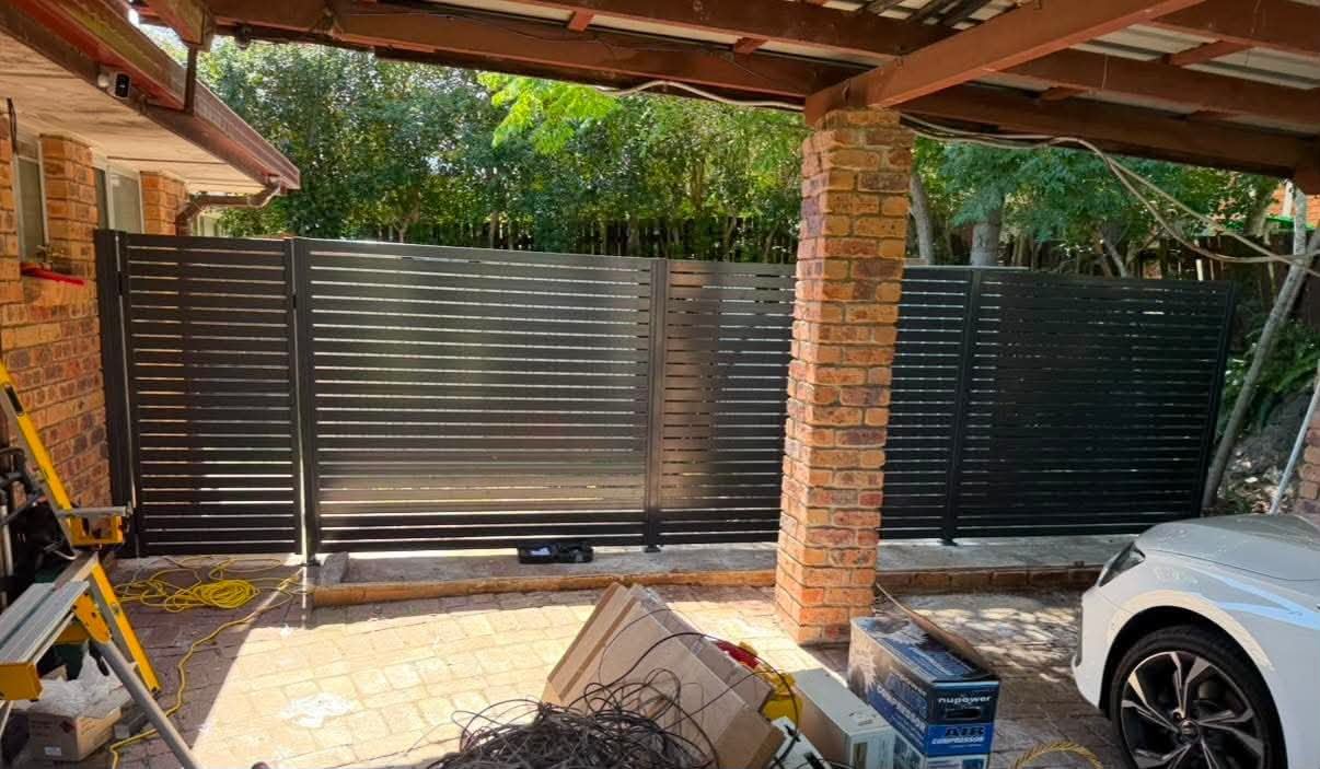 Dark Colorbond pedestrian gate fitted between brick columns
