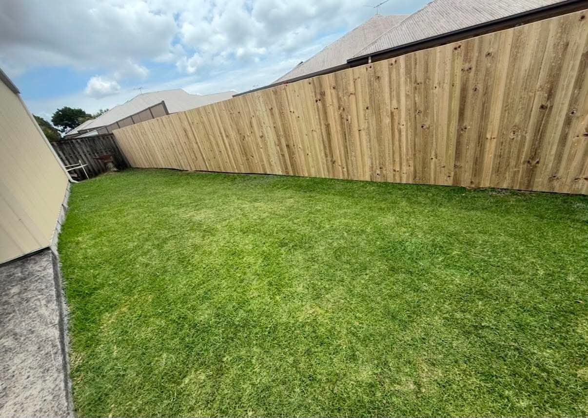 Long timber boundary fence beside a residential lawn