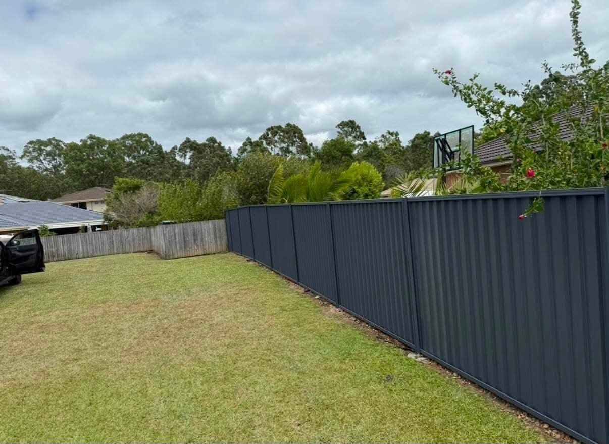 Completed dark Colorbond fence across a sloping rear boundary