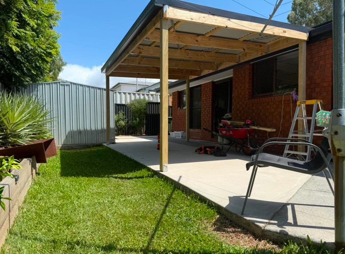 Carport extension with exposed timber rafters providing additional undercover space next to an existing home